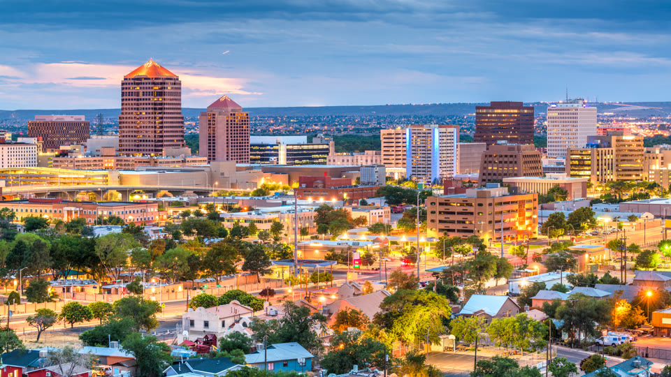 Albuquerque, New Mexico downtown skyline at dusk with the Sandia foothills behind it