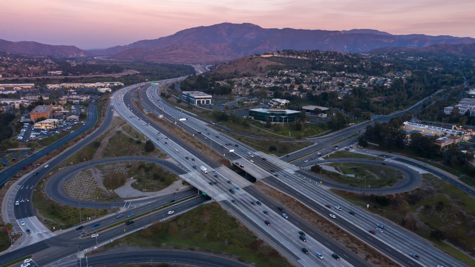 The 91 Freeway at twilight through Anaheim Hills, with the Santa Ana Mountains behind, in Anaheim, California