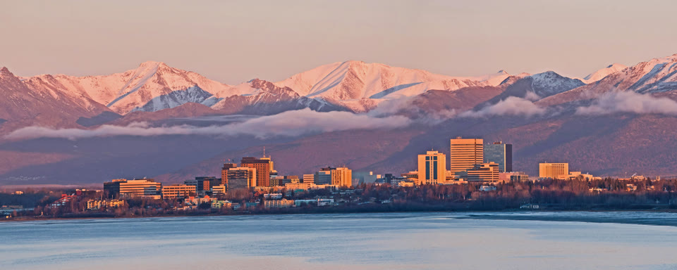 Anchorage, Alaska skyline at sunset with the snow-capped Chugach Mountains behind it
