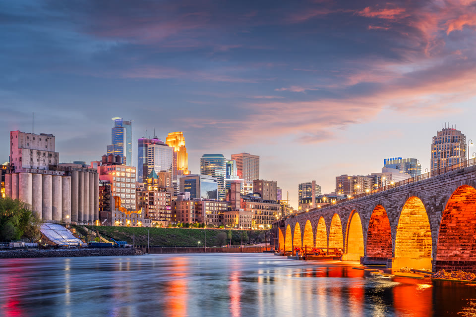 Minneapolis, Minnesota skyline at dusk viewed across the Stone Arch Bridge